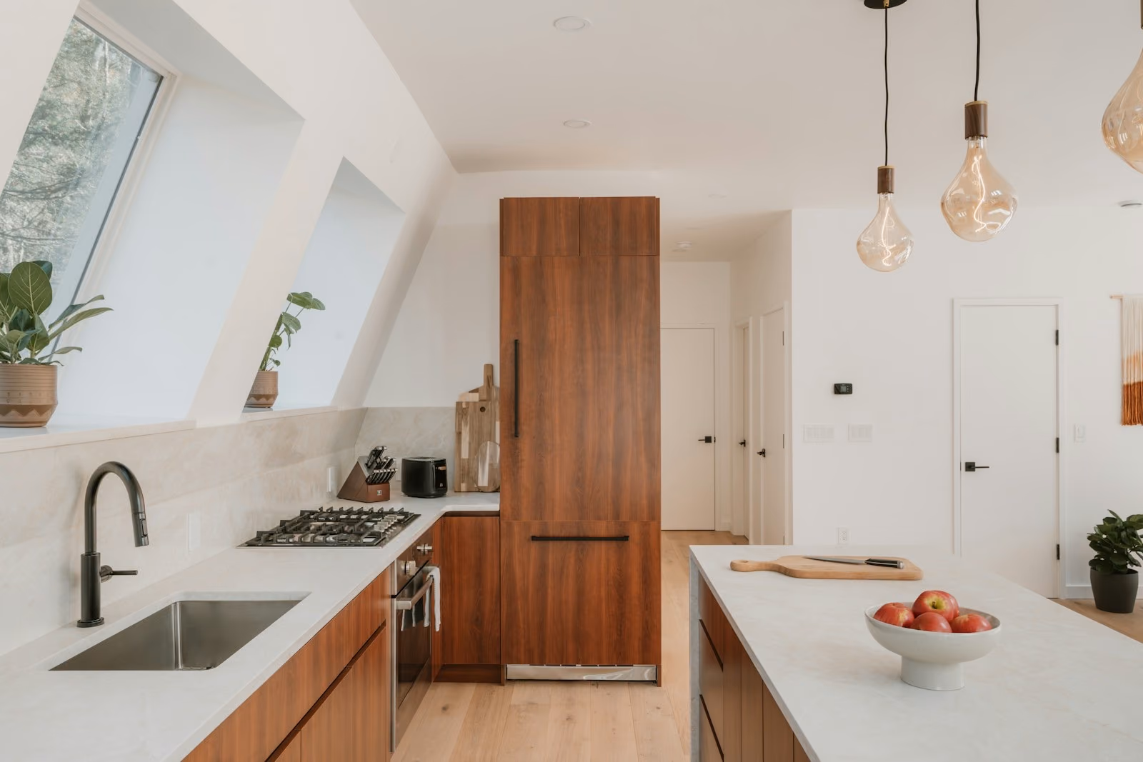 Cocina reformada con muebles de madera clara, isla central y encimera de piedra