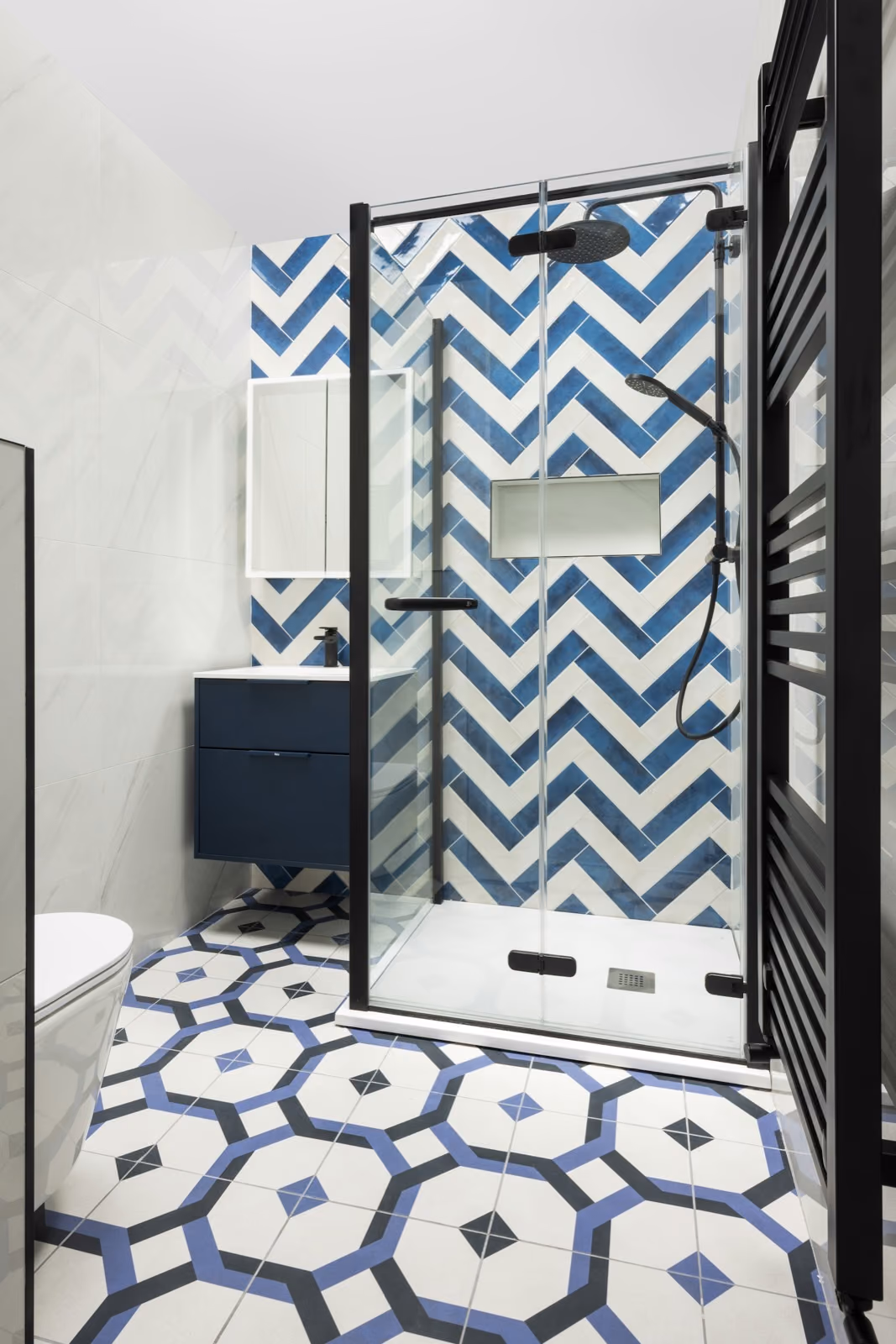 Azulejos azules en espiga y suelo hidráulico geométrico en un baño recién alicatado
